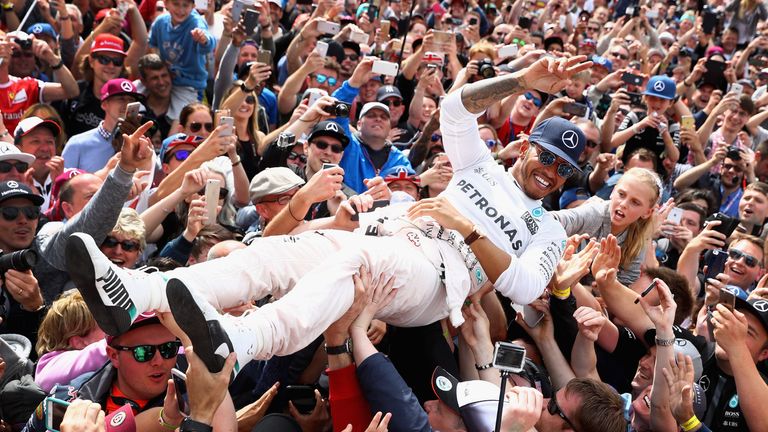 NORTHAMPTON, ENGLAND - JULY 10:  Lewis Hamilton of Great Britain and Mercedes GP celebrates his win with fans on the start finish straight after the Formul