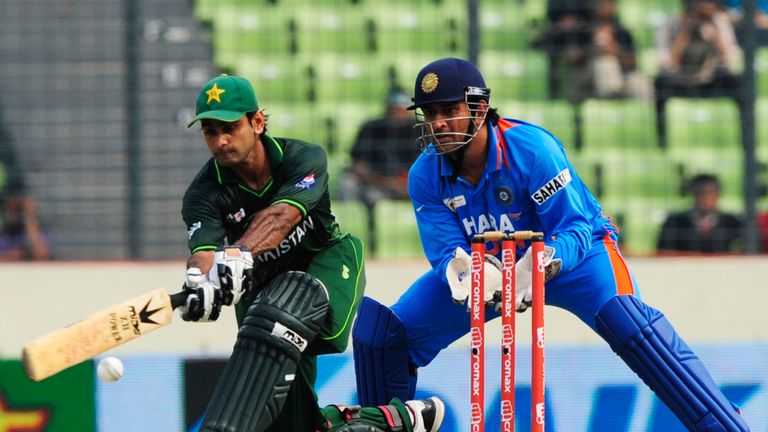 Pakistan's Mohammad Hafeez (L) plays a shot as Indian captain Mahendra Singh Dhoni (R) reacts during the one day international (ODI) Asia Cup cricket