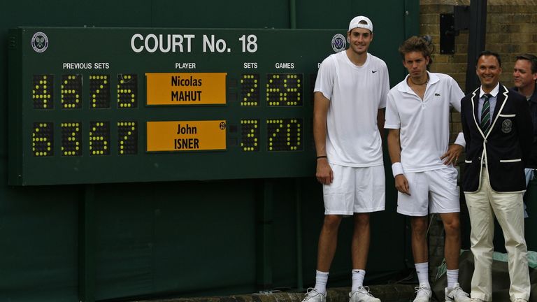 John Isner of the US (L), France's Nicolas Mahut (2nd L), and chair umpire Mohamed Lahyani (2nd R), pose with the score board at the end of their match