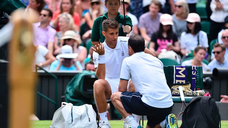 Slovakia's Martin Klizan talks with the physio before retiring during his men's singles first round match against Serbia's Novak Djokovic on the second day