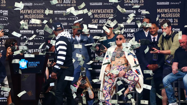 Floyd Mayweather Jr. looks on as money rains down on Conor McGregor during the Floyd Mayweather Jr. v Conor McGregor World Press Tour