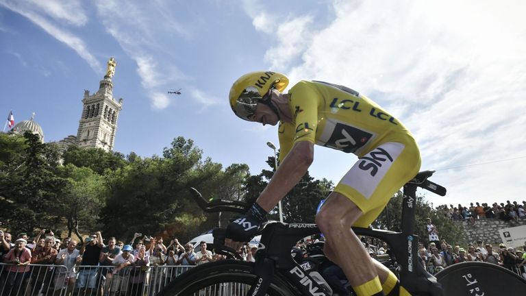 Chris Froome, wearing the overall leader's yellow jersey, rides past the Notre-Dame de la Garde basilica (L) as he competes in a 22,5km time trial
