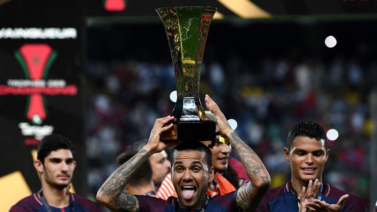 Paris Saint-Germain's Brazilian defender Dani Alves holds the trophy as he celebrates with teammates after winning the French Trophy of Champions (Trophee 