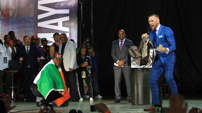 Floyd Mayweather Jr. is draped in an Irish flag while Conor McGregor goes through his bag