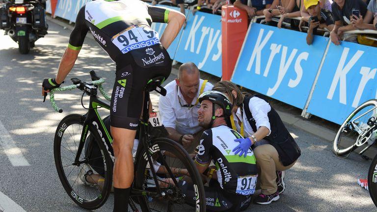 Great Britain's Mark Cavendish (C), speaks with his teammate Austria's Bernhard Eisel as he receives medical assistance after falling near the finish line 