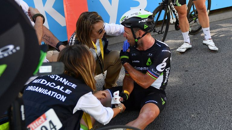 Great Britain's Mark Cavendish (C), receives medical assistance after falling near the finish line at the end of the 207,5 km fourth stage of the 104th edi