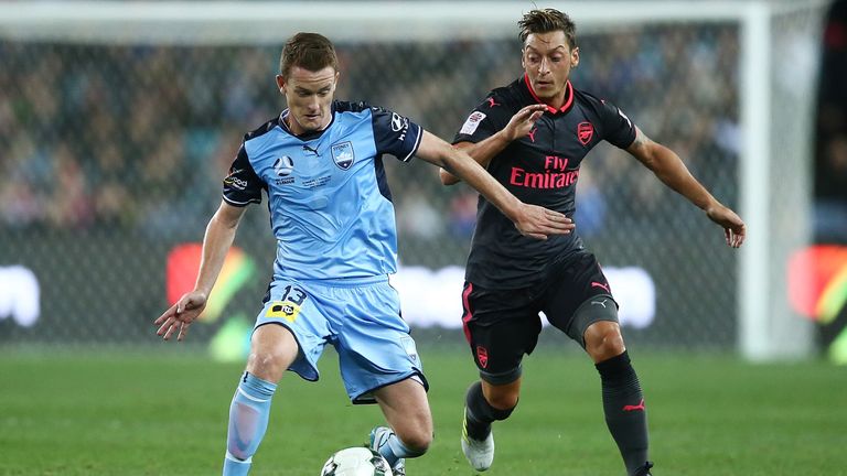 Mesut Ozil challenges Brandon O'Neill during the first half