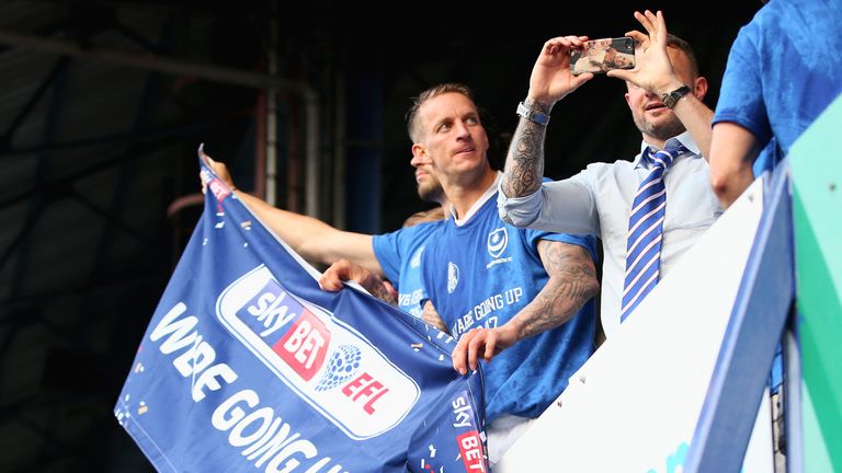 PORTSMOUTH, ENGLAND - MAY 6: Carl Baker of Portsmouth holds a promotion banner after  the Sky Bet League Two match between Portsmouth and Cheltenham Town 