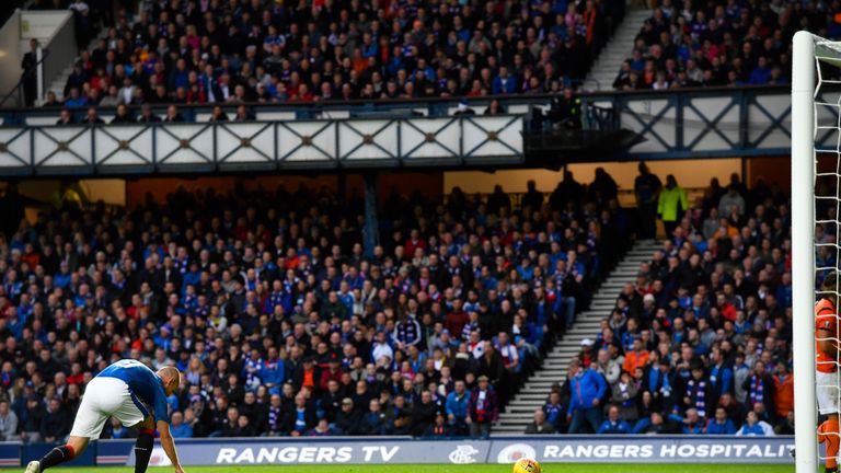 Rangers' Kenny Miller collects paper that was thrown onto the pitch