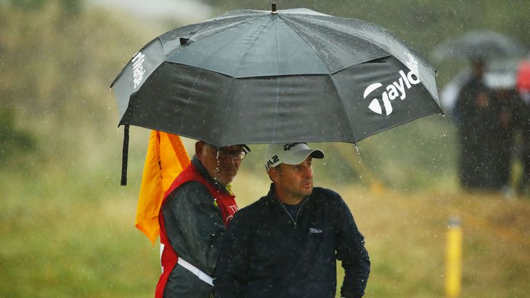 Richard Bland of England waits with his caddie under an umbrella during the second round of The 146th Open 