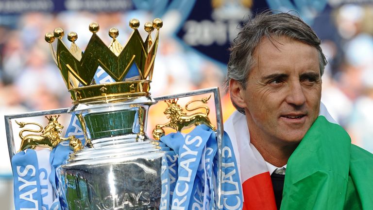 Manchester City's Italian manager Roberto Mancini celebrate with the Premier League trophy on the pitch after their 3-2 victory over Queens Park Rangers in