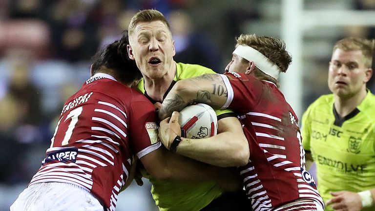 Hull FC's Chis Green is tackled by Wigan Warriors Taulima Tautai (L) and Sam Powell (R) during the Betfred Super League match at the DW Stadium