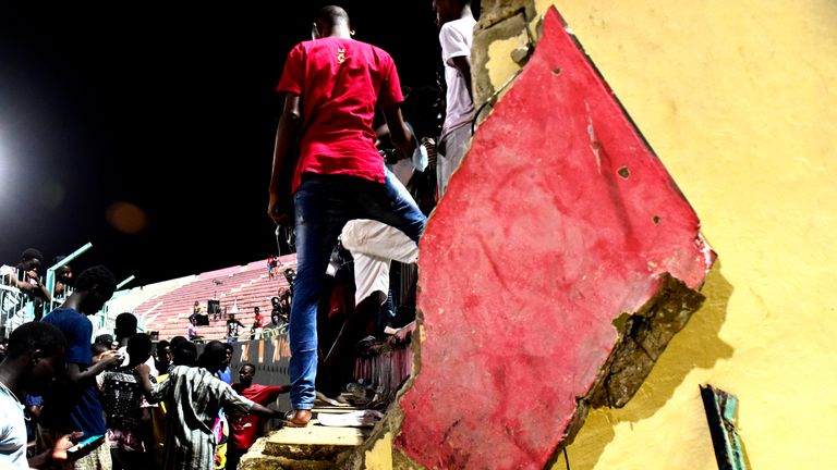 People stand amid a collapsed wall at Demba Diop stadium July 15, 2017 in Dakar after a football game between local teams Ouakam and Stade de Mbour.

