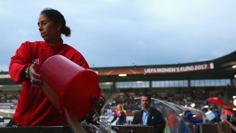 Germany head coach Steffi Jones helps to remove rain water