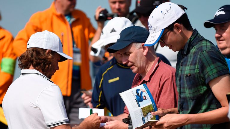 England's Tommy Fleetwood (L) signs autographs for fans during a practice round at Royal Birkdale golf course near Southport in north west England on July 