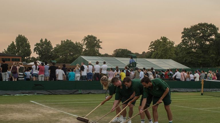 Ground staff sweep loose dirt along the baseline in the outside courts by the end of day four of the Wimbledon Lawn Tennis Championships