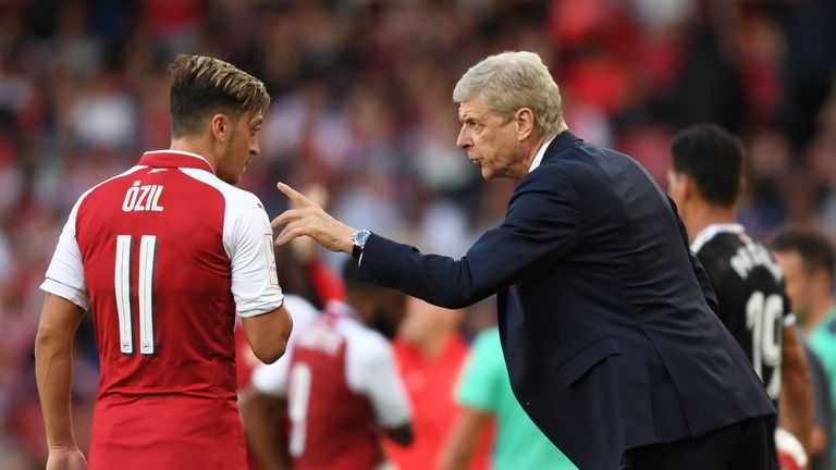 Arsene Wenger speaks to Mesut Ozil during a pre-season game