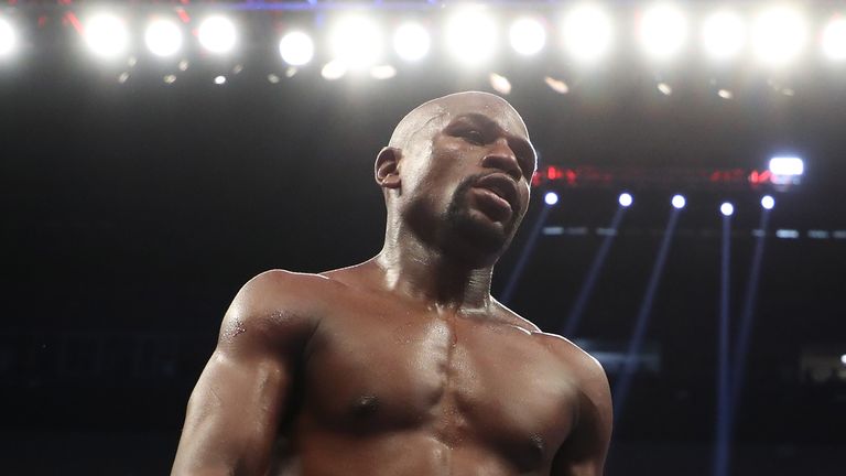 (L-R) Floyd Mayweather Jr. walks to his corner in between rounds of his super welterweight boxing match against Conor McGregor 