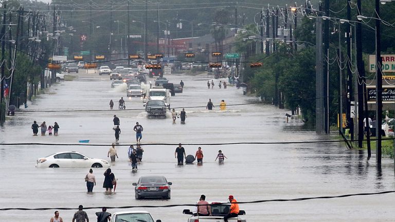 TOPSHOT - People walk through the flooded waters of Telephone Rd. in Houston on August 27, 2017 as the US fourth city city battles with tropical storm Harv