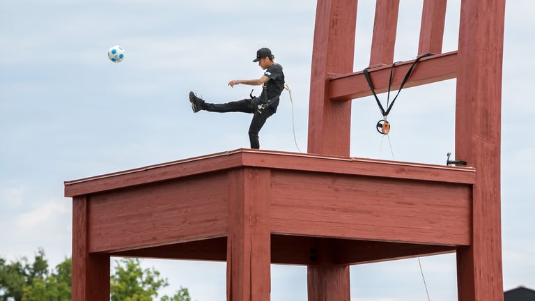 Brazilian superstar and world's most expensive footballer Neymar shoots a ball on the monumental wood sculpture "Broken Chair" during an event