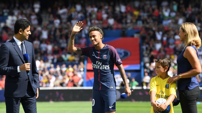 Paris Saint-Germain's Brazilian forward Neymar (C), flanked by Paris Saint Germain's (PSG) Qatari president Nasser Al-Khelaifi (L), waves to the crowd duri