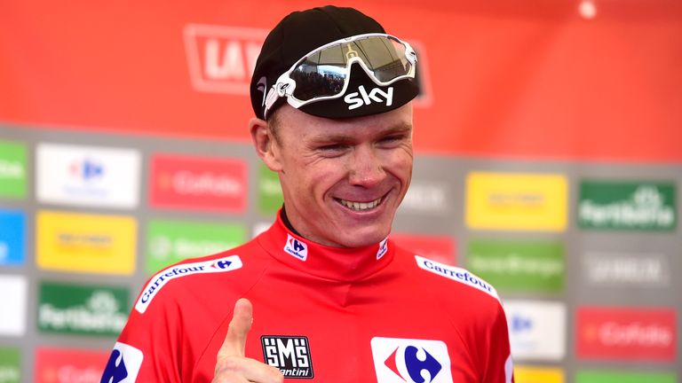 Sky's British cyclist Christopher Froome smiles as he sports the overall leader's red jersey on the podium of the 20th stage of the 72nd edition of "La Vue