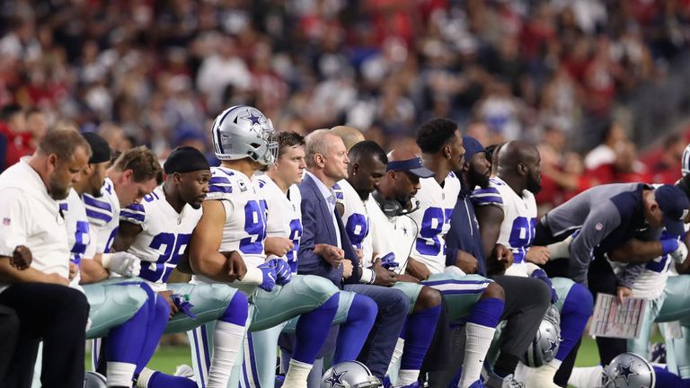  Dallas Cowboys link arms before kneeling ahead of the national anthem