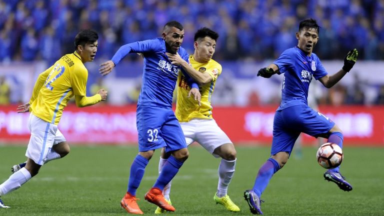 Shanghai Shenhua striker Carlos Tevez (2L) fights for the ball with Yang Xiaotian (2R) of Jiangsu Suning during the Chinese Super League on March 5, 2017.