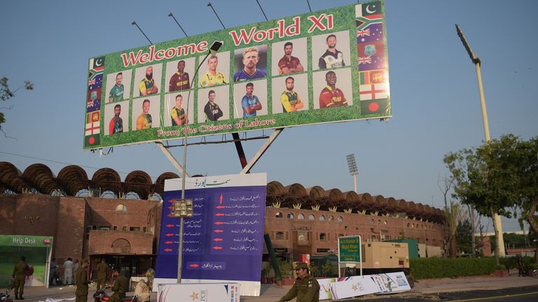 Pakistani policemen ride past a billboard featuring International World XI cricketers displaying outside the Gaddafi Cricket Stadium in Lahore on September