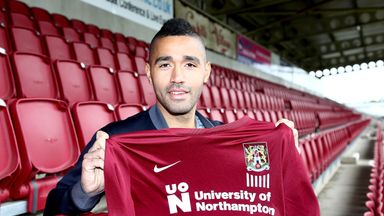 Image of Lewis McGugan poses with a shirt during a photo call at Sixfields