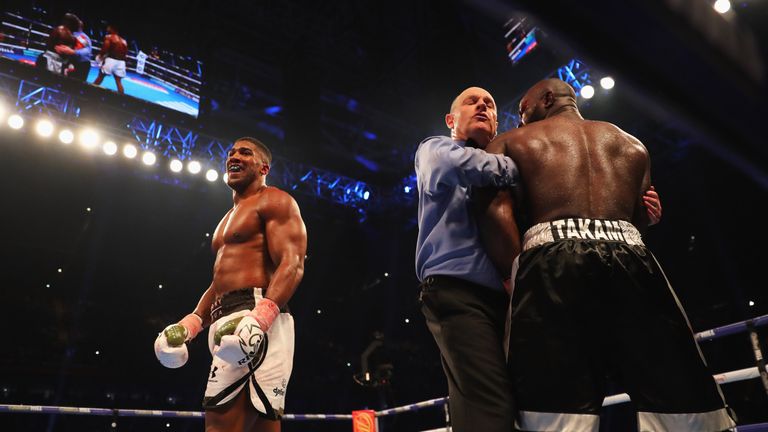 CARDIFF, WALES - OCTOBER 28:  Anthony Joshua looks on as referee Phil Edwards holds Carlos Takam as he stops the fight in the 10th round during the IBF, WB