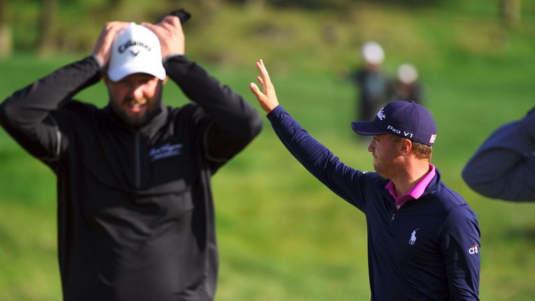 Justin Thomas of the US (R) waves to celebrate his victory as Marc Leishman of Australia walks on the 18th green at the end of the CJ Cup golf tournament a
