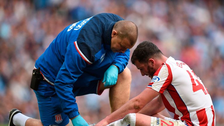 Stoke City's English defender Tom Edwards (R) gets attention on the pitch for an injury during the English Premier League football match between Manchester