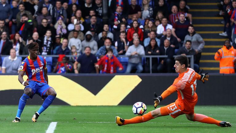 LONDON, ENGLAND - OCTOBER 14: Wilfried Zaha of Crystal Palace scores his sides second goal past Thibaut Courtois of Chelsea during the Premier League match