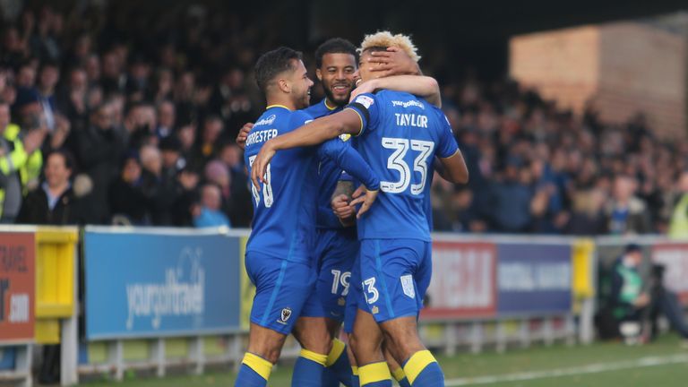 Lyle Taylor #33 of AFC Wimbledon celebrates scoring his side's first goal with team-mates during the Sky Bet League One clash v Peterborough United 