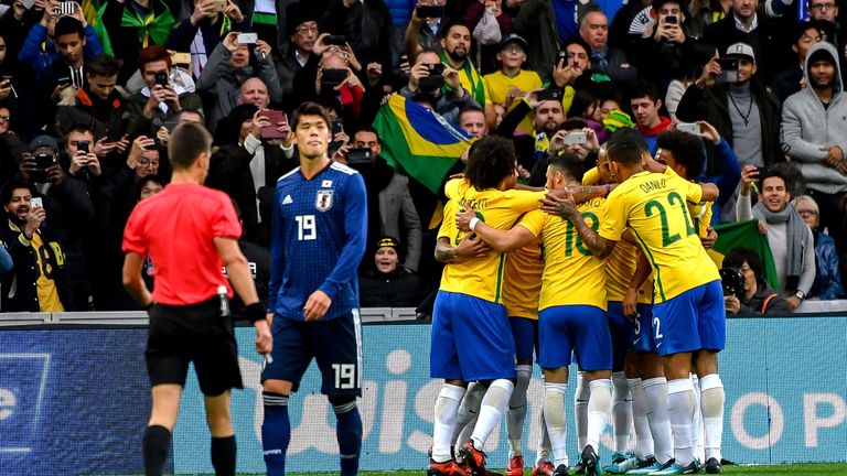 Neymar is mobbed by his team-mates after scoring from the penalty spot against Japan