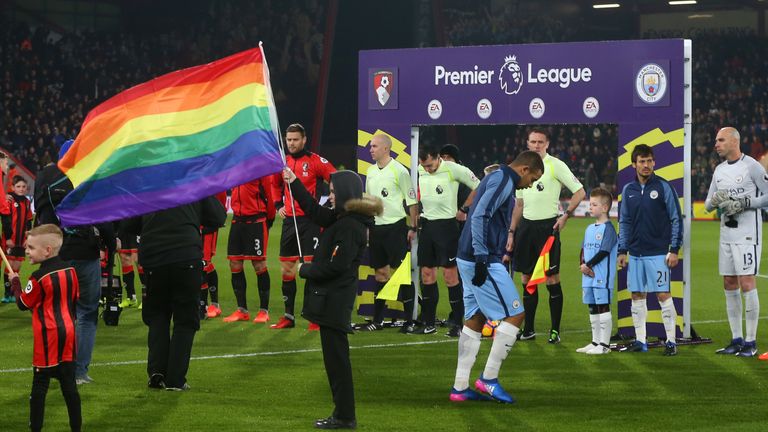 A rainbow flag is held up next to the Premier League Board as the players line up during the match between Bournemouth and Manchester City, February 2017