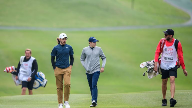 Tommy Fleetwood of England (2nd L) walks on the fairway with his compatriot Matthew Fitzpatrick (C) during round one of the Hong Kong Open at the Hong Kong