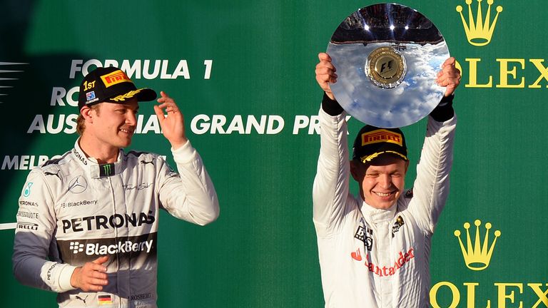 Third-placed McLaren driver Kevin Magnussen of Denmark (R) holds his trophy aloft on the podium as winner Mercedes driver Nico Rosberg of Germany (L) looks