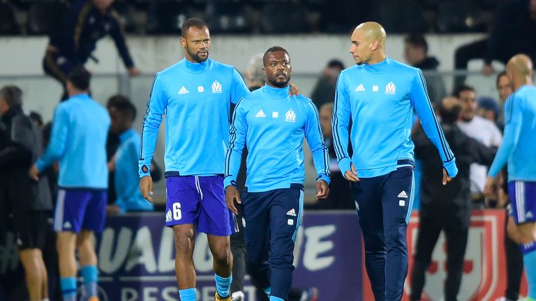 Marseille's French defender Patrice Evra (C) is escorted off the pitch by teammates Portuguese defender Rolando and Brazilian defender Doria after an argum