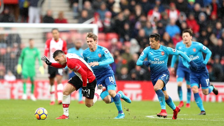 Dusan Tadic tires to break away from Nacho Monreal and Alexis Sanchez