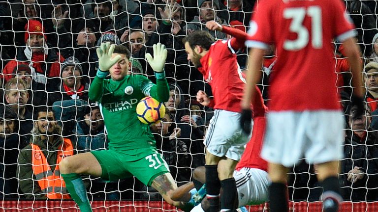 Manchester City's Brazilian goalkeeper Ederson (L) makes the second of a double save from a shot from Manchester United's Spanish midfielder Juan Mata (2L)