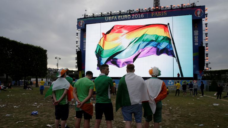 Supporters in front of a giant screen displaying a rainbow flag to pay tribute to the victims of the Orlando attack, in a Paris fan zone during Euro 2016