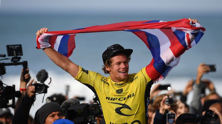 Hawaian surfer John John Florence waves his country's flag after securing the World Surf League World Title at Supertubos beach near Peniche, central Portu
