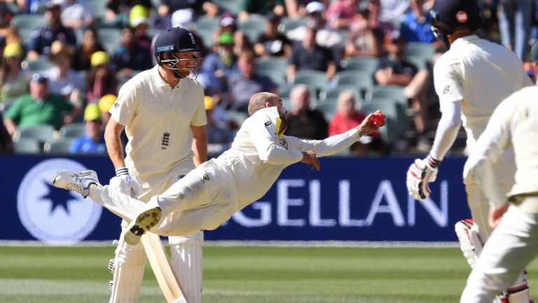 Australian spinner Nathan Lyon (C) dives to take a catch to dismiss England batsman Moeen Ali (2/R) as fellow batsman Jonny Bairstow (L) looks on on the th