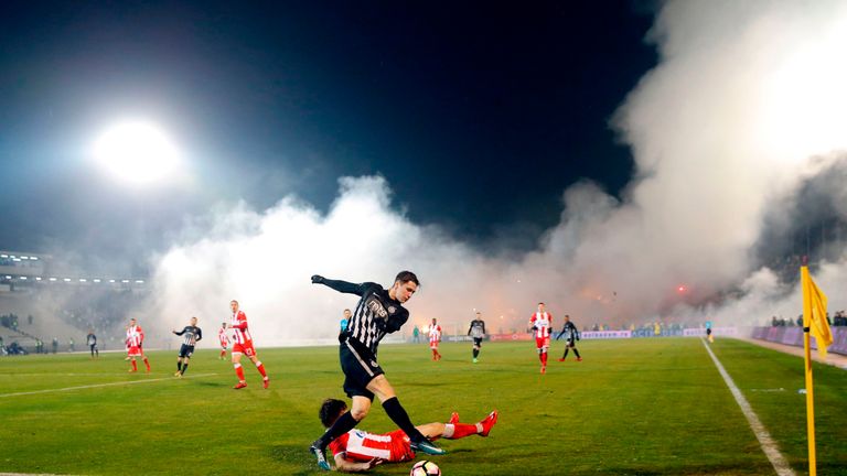 Partizan's Marko Jevtovic (L) vies with Crvena Zvezda's Filip Stojkovic (bottom) as smoke rise from the stands during the Serbian Superleague derby