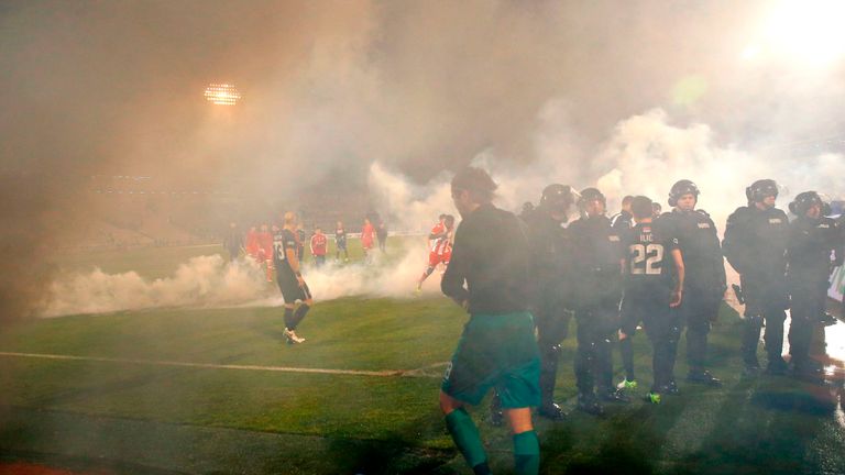 Policemen and players are engulfed in smoke after two groups of Partizan Belgrade's hooligans clashed with each other during the Serbian Superleague derby 