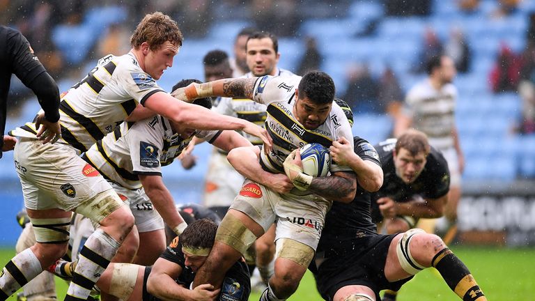 COVENTRY, ENGLAND - DECEMBER 17:  Afa Amosa of La Rochelle is tackled by Thomas Young (L) and James Gaskell (R) of Wasps during the European Rugby Champion