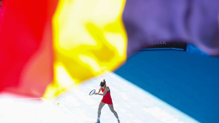 MELBOURNE, AUSTRALIA - JANUARY 25:  Simona Halep of Romania plays a shot as the Flag of Romania waves in the air in her semi-final match against Angelique 