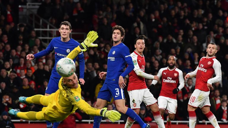 Arsenal's German midfielder Mesut Ozil (C) watches as he misses a shot at goal as Chelsea's Argentinian goalkeeper Willy Caballero (L) dives during the Lea